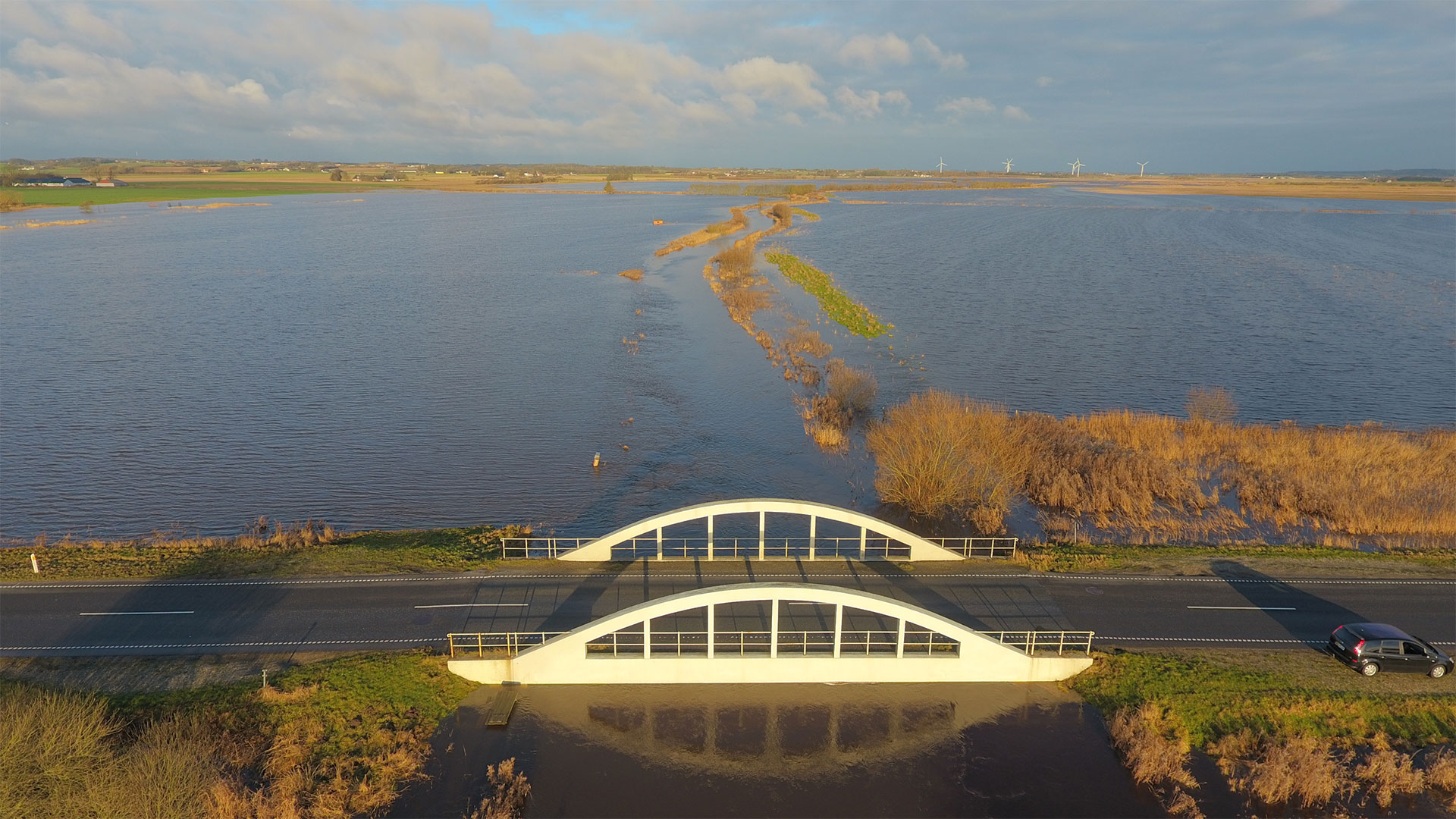 Floods in a flat landscape where a bridge is almost submerged. Photo: Jammerbugt Kommune